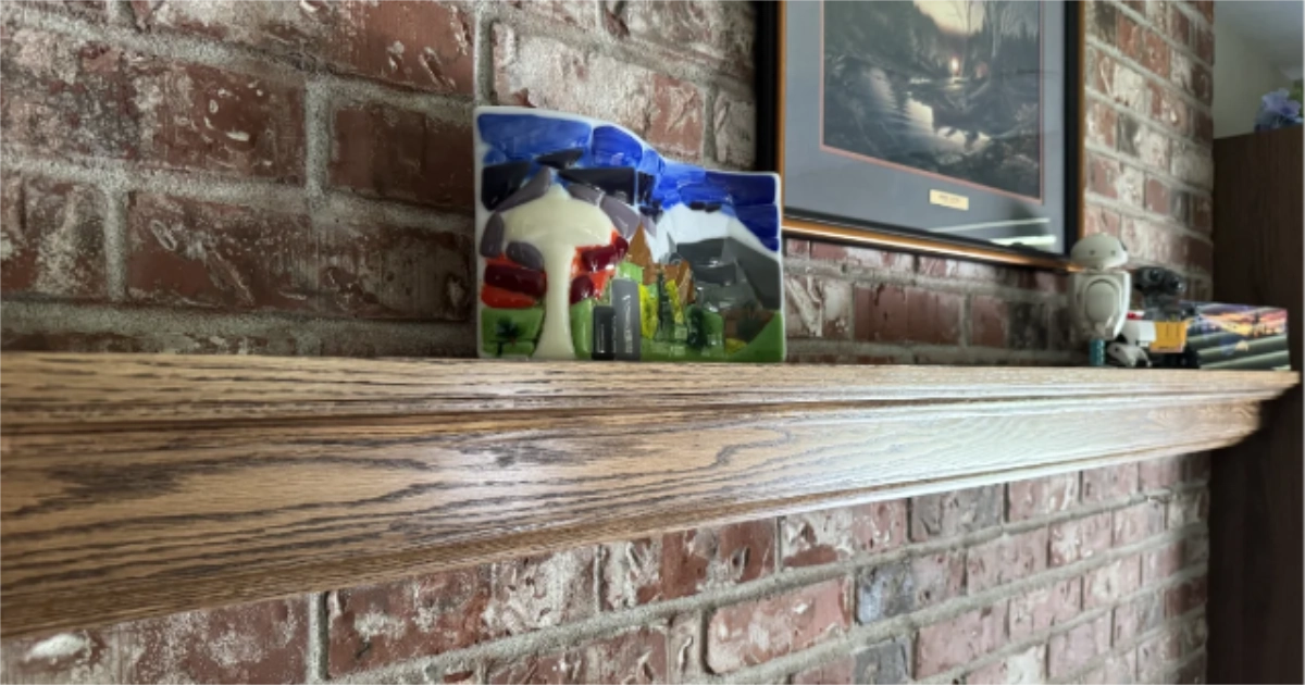 Stained oak fireplace mantel with some art and Legos on it